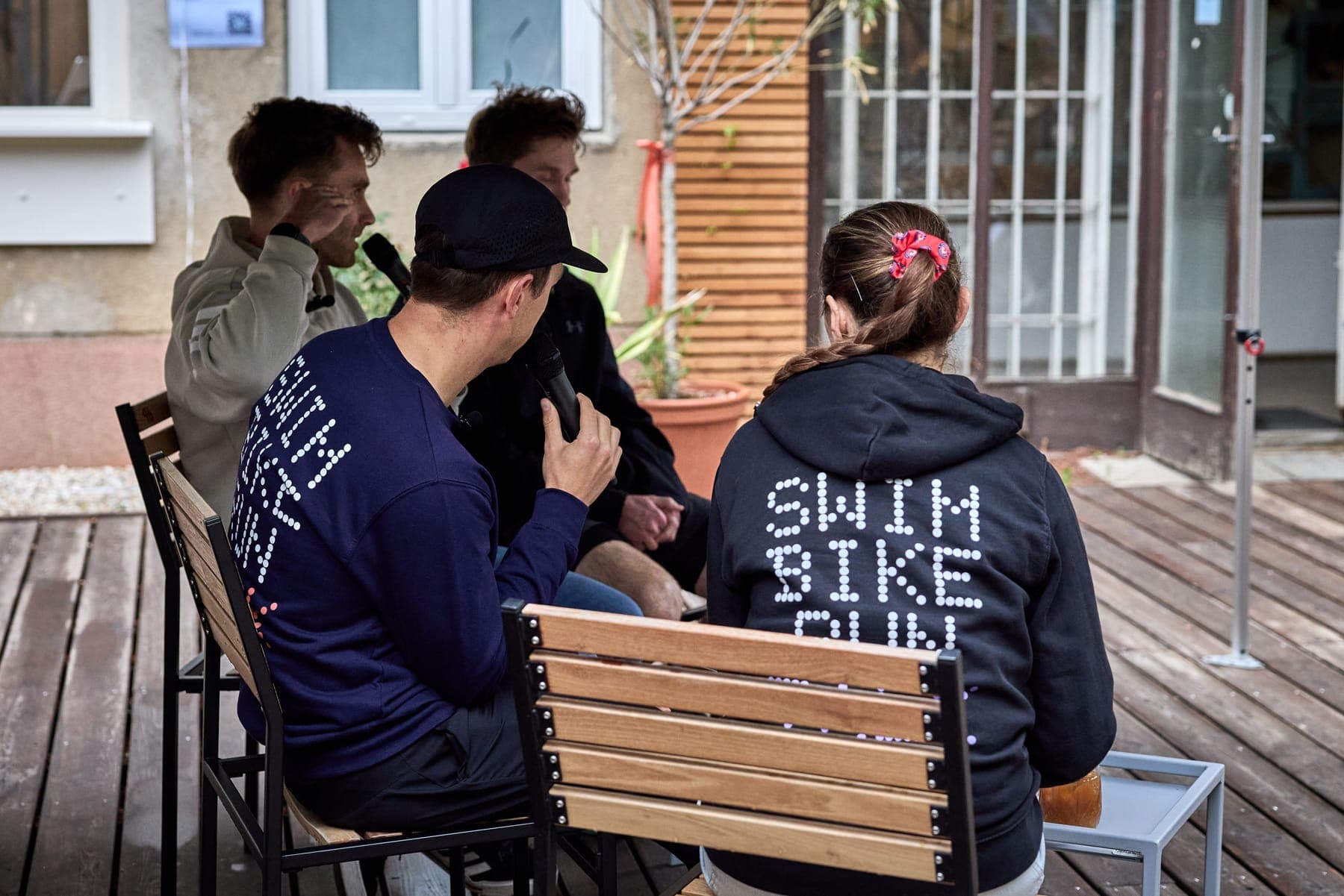 Kája a Sam zezadu, na Kájině mikině nápis Swim Bike Run, naproti nim hosté z Hyve